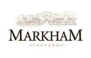 The logo of Markham Vineyards, featuring the name "Markham" in prominent, stylized lettering. Beneath it, the word "Vineyards" is displayed in a smaller font. The logo includes a sketch of a building and vineyard landscape in the background.