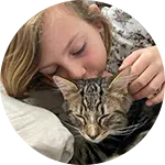 A young girl gently kissing and cuddling a tabby cat on a couch, with her hand resting on the cat’s back. The scene highlights a bond between them, emphasizing the importance of animal rescue donations for providing care and support.