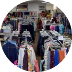 An interior view of a clothing donation center, featuring multiple racks filled with a variety of clothing items. Brightly colored shirts and pants are displayed neatly, emphasizing the available options for animal rescue donations.