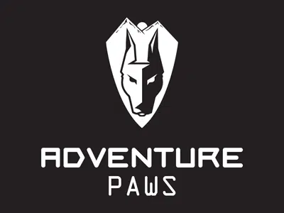 A logo for "Adventure Paws" featuring a stylized wolf head inside a shield. The design is in black and white, with the text "ADVENTURE" at the top and "PAWS" at the bottom in bold, modern font.