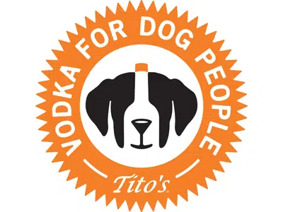 An orange circular Tito's Vodka for Dog People logo with a black-and-white dog face in the center on a white background.