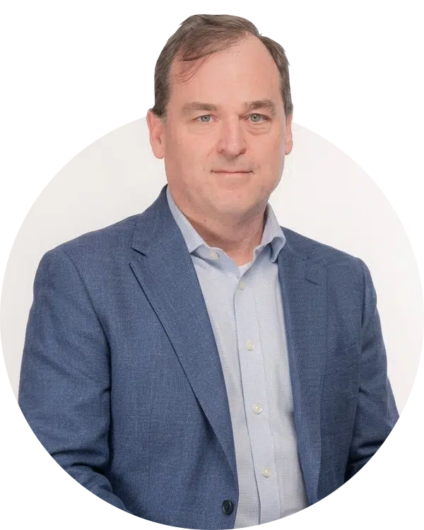 A man in a blue blazer and light shirt posed against a white circular background for the Joybound Board of Directors.
