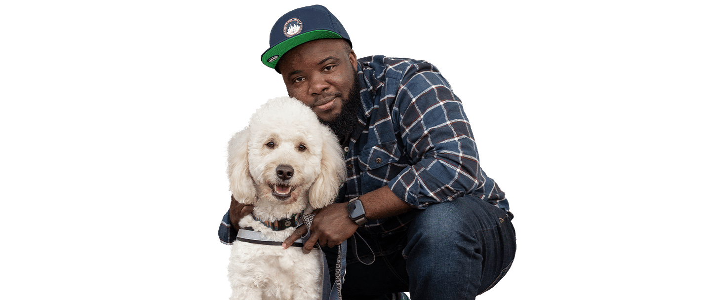 A man kneels beside a white dog, shown as an example of Emotional support animals, against a black background.